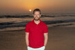 happy bearded handsome man in summer shirt on beach with sunset over sea, summer