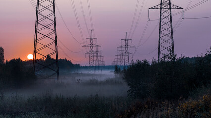 High voltage power poles of electricity in the morning fog in autumn