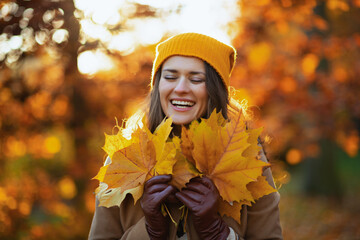 Wall Mural - happy trendy woman in beige coat and orange hat