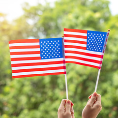 Wall Mural - hand holding United States of America flag on green background. USA holiday of Veterans, Memorial, Independence ( Fourth of July) and Labor Day concept