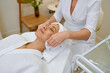 © Tatiana Timofeeva/Stocksy - Cosmetologist doing face massage adult woman patient in beauty salon
