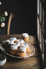 Vanilla Cupcakes On A Rustic Wooden Table By The Window