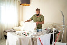 Hipster Man Hanging Clothes At Living Room