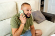 © Eloisa Ramos/Stocksy - Young man smiling calling by phone at home