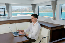 Businessman Working On Laptop In Cabin Of Yacht