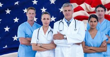 Composition Of Smiling Diverse Team Of Medical Workers Over Billowing American Flag