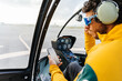 © Marcos Osorio/Stocksy - Helicopter pilot with sunglasses checking the smartphone