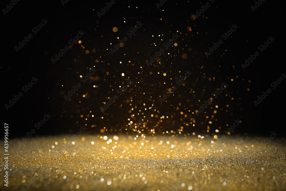 Shiny golden glitter falling down on black background. Bokeh effect - obrazy, fototapety, plakaty 