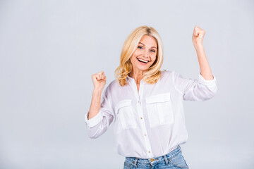I'm winner! Portrait of a cheerful happy senior mature woman gesturing victory isolated over white grey background.