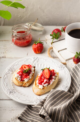 Poster - Homemade bruschetta with cottage cheese and strawberries for breakfast at white wooden background