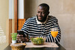 © Ezequiel Giménez/Stocksy - African Man Using his Phone in Cafeteria