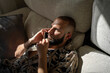 © Eloisa Ramos/Stocksy - Modern man calling by phone lying on the sofa