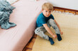 © Olga Moreira/Stocksy - 5 years old boy sittin on the floor while getting dressed