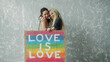 © iaginzburg - Female lesbian couple holding colorful LGBT poster