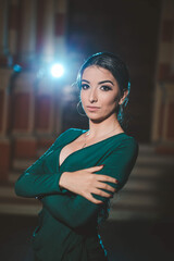 Wall Mural - Vertical shot of a young elegant female in a green dress posing outdoors