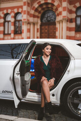 Canvas Print - Vertical shot of a young elegant female in a green dress posing in a limousine