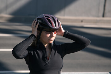 Wall Mural - A porter of a female cyclist, illuminated by the morning sun, poses after a workout. Sports in the city. Morning cycling workout. Sport equipment. Sports portrait.