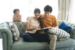 © Kris Tan - Asian Parents and a kid child look at a laptop at home. Family concept.
