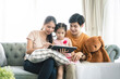 © Kris Tan - Asian Parents and a kid child look at a laptop at home. Family concept.