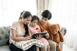 © Kris Tan - Asian Parents and a kid child look at a laptop at home. Family concept.