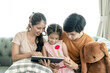 © Kris Tan - Asian Parents and a kid child look at a laptop at home. Family concept.