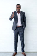 Full length image of African business man showing thumb up gesture on white background