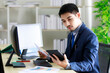 © Bangkok Click Studio - Successful young Asian businessman smiles happily while seeing good news on tablet in office. Business and success concept.