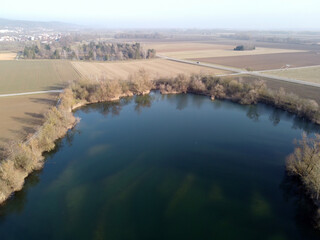 Poster - Aerial shot of a lake, agricultural fields and a little town in a distance