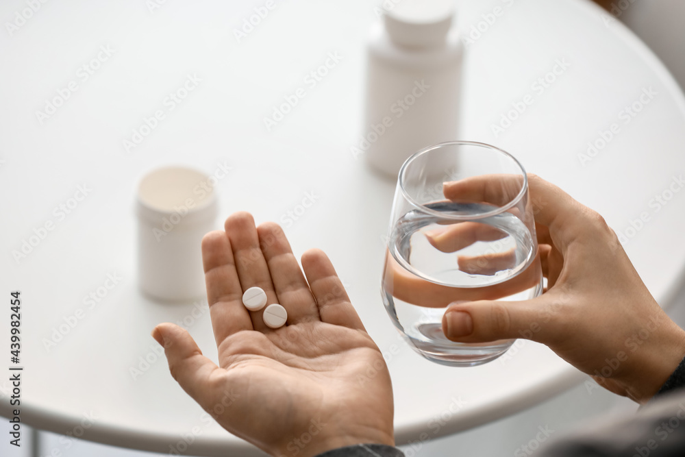 Woman taking pills at home, closeup