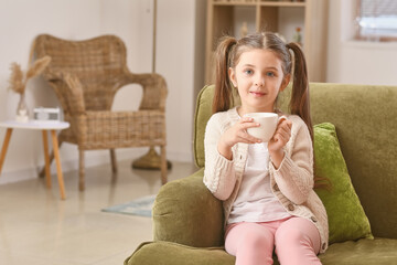 Cute little girl drinking tea at home