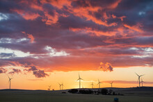 Wind Turbines In Farmland Against Sunset Sky