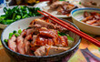 Cantonese roast duck, honey roast pork with vegetables and rice in a bow.