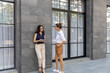 © Ron - Two attractive girls in smart casual having conversation on a side walk in the city next to business building.