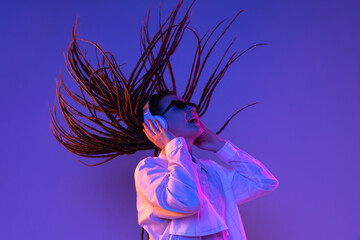 Caucasian young woman's portrait on dark studio background in neon. Concept of human emotions, facial expression.