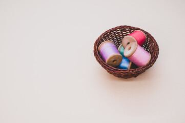 Wall Mural - Basket of colorful sewing threads on a light background with free space for text