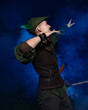 © ISliM - Cosplay on Peter Pan. A young man in a Peter Pan costume stands amid blue smoke at night