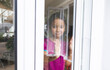 © Wavebreak Media - Hispanic girl standing at window with hands on glass, looking out and making sad face
