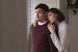 © Wavebreak Media - Thoughtful hispanic couple standing at window looking out and embracing