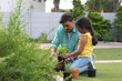 © Wavebreak Media - Smiling hispanic father and daughter gardening, kneeling and planting in flower bed