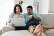 © Wavebreak Media - Hispanic couple relaxing on couch using laptop computer together