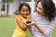 © Wavebreak Media - Smiling hispanic mother and daughter gardening, mother holding seedling in hand