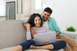 © Wavebreak Media - Smiling hispanic couple sitting on couch using laptop together