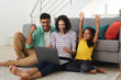 © Wavebreak Media - Cheering hispanic mother, father and daughter sitting on living room floor using laptop together