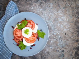 Wall Mural - Italian caprese salad with sliced tomatoes, mozzarella, basil, olive oil on a blank plate. View from above.