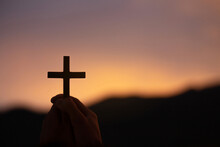 Christian, Christianity,  Silhouette Of Hands Holding Wooden Cross For Worshipping God At Sunset Background.spirituality And Religion. Peace, Hope, Dreams Concept
