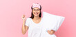 hispanic woman wearing pajamas feeling shocked,laughing and celebrating success and holding a pillow