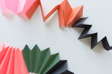 abstract construction paper zig-zag objects or fans isolated on white in green pink orange and black