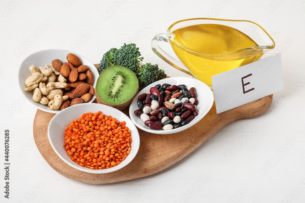 Board with healthy products rich in vitamin E on light wooden background