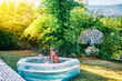 Caucasian child enjoying in the water of an inflatable pool in the home garden at summer evening