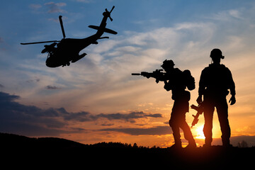 Silhouette of a soldiers and helicopter on the background of sunset. Concept - protection, patriotism, honor.